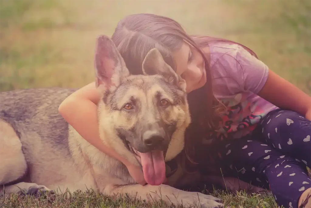 Young girls cuddling with adult German Shepherd Dog, showcasing the breed's gentle family bond that makes the investment in proper care worthwhile